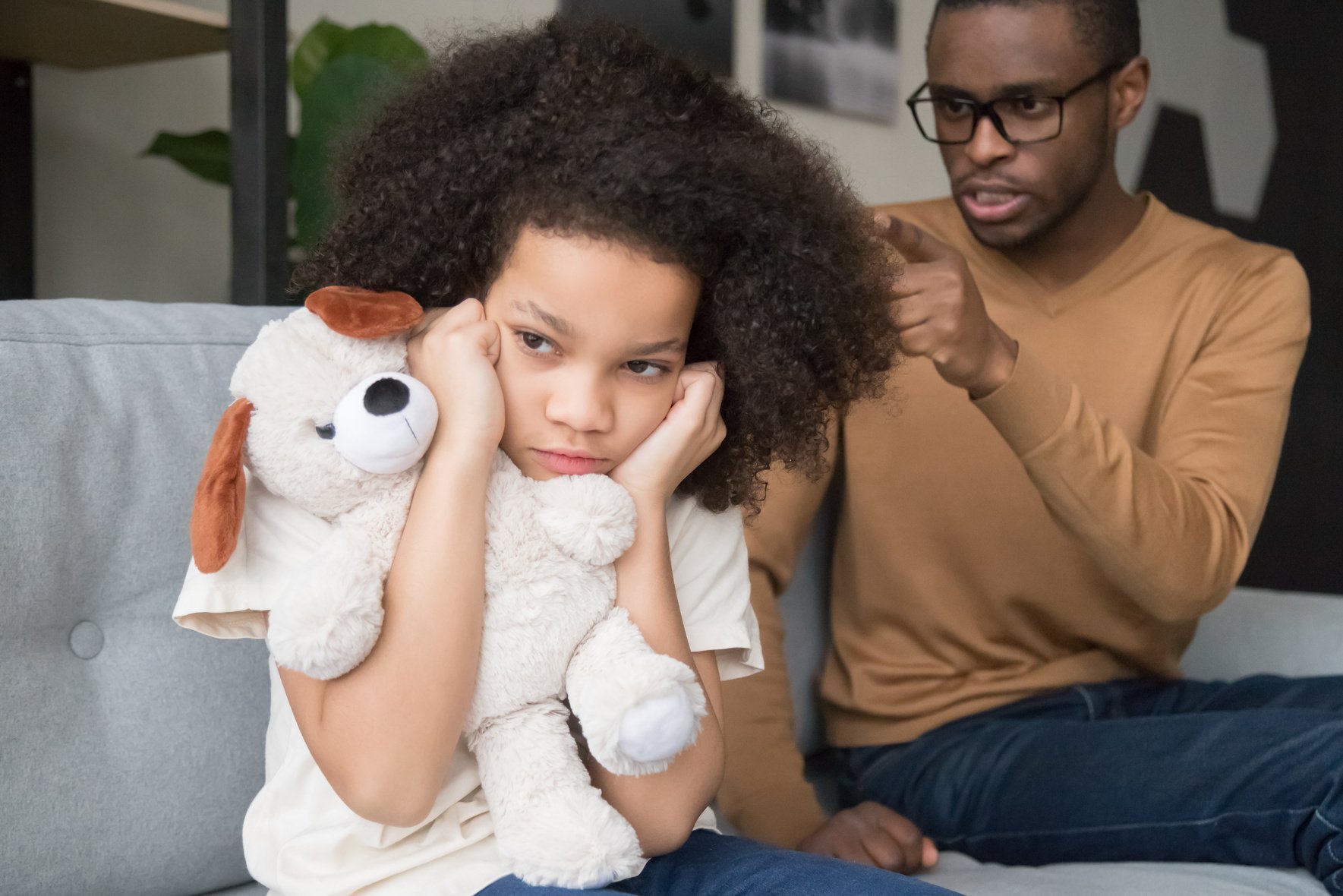 Stubborn african child girl closing ears ignoring angry black dad